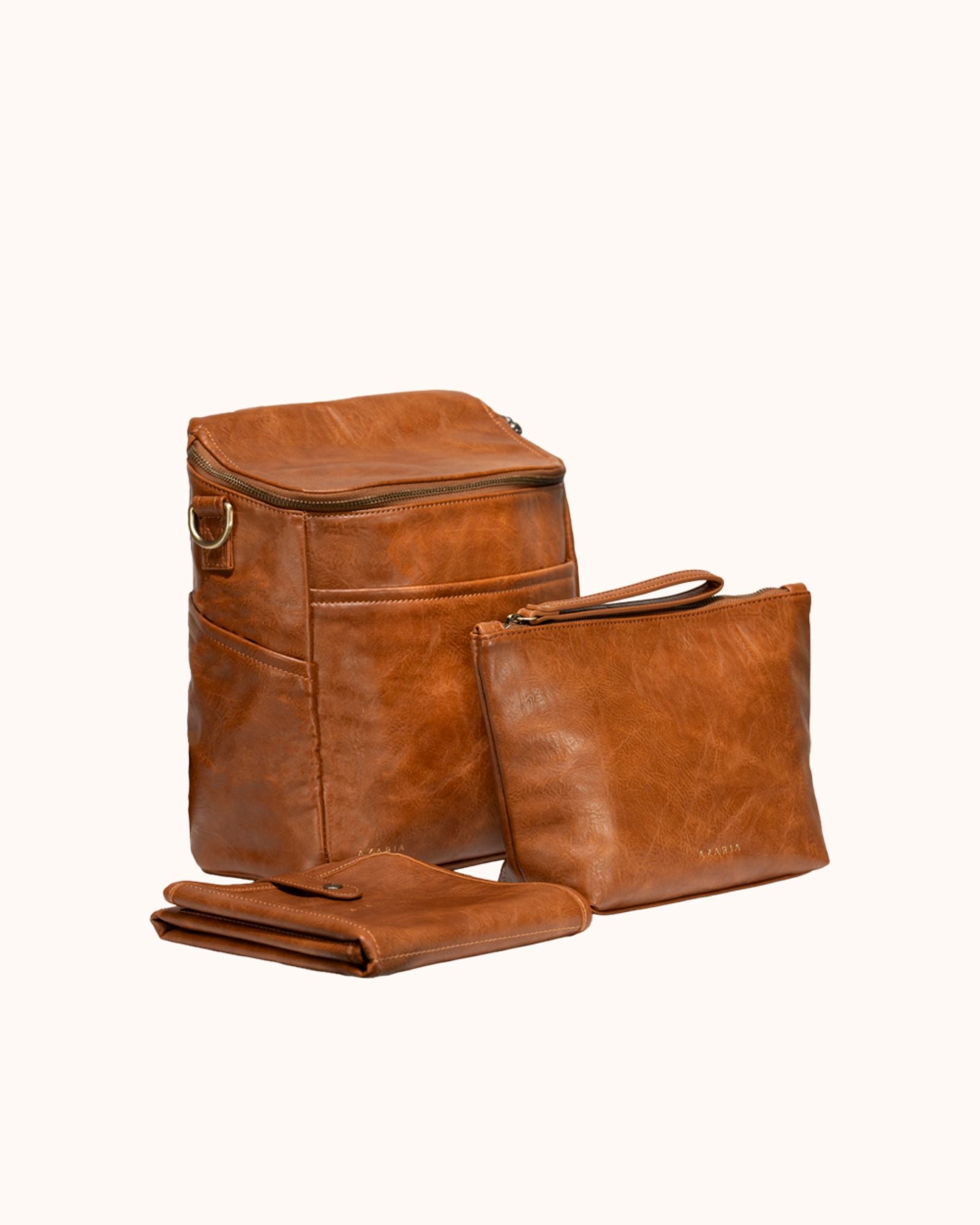 Set of brown vegan leather bags including a backpack, pouch, and folded mat on a white background