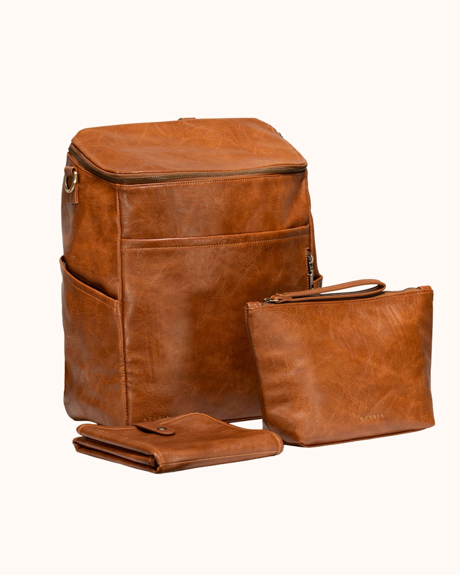 Brown leather backpack, pouch, and wallet on a white background