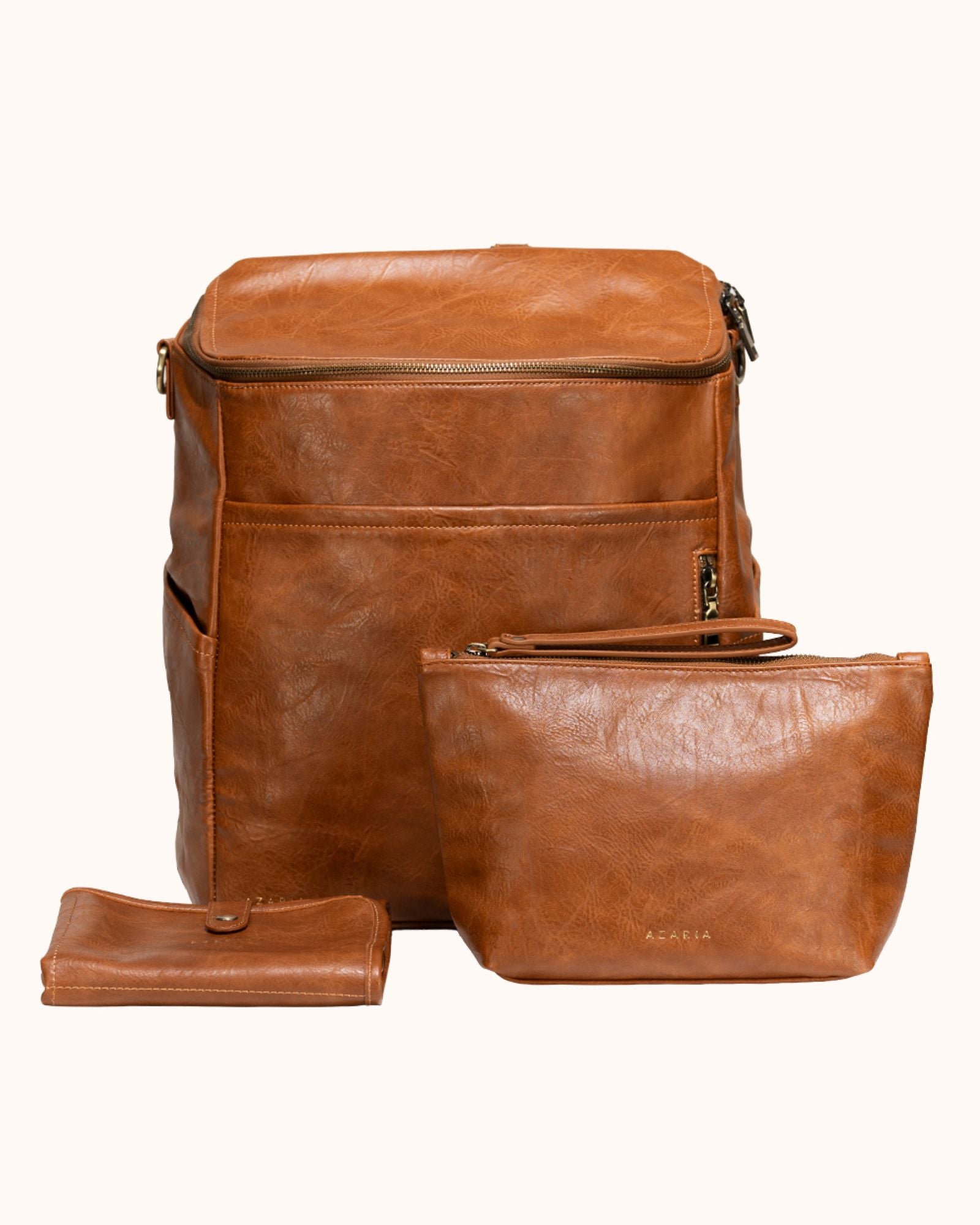 Brown leather backpack with matching pouch and wallet on a white background